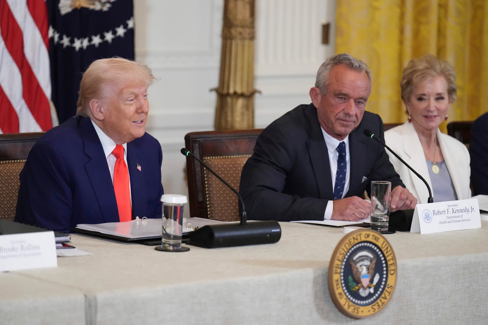 AP/Jacquelyn Martin President Trump, left, speaks as Education Secretary Linda McMahon, right, and Health and Human Services Secretary Robert F. Kennedy Jr. listen at a Make America Healthy Again Commission Event.