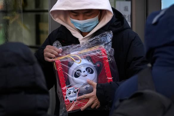 A man holds a Bing Dwen Dwen doll purchased from a store selling 2022 Winter Olympics memorabilia in Beijing, February 7, 2022. AP/Andy Wong