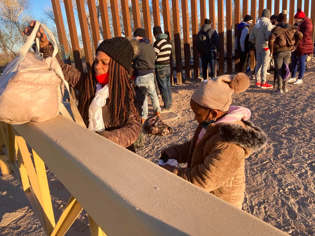 A Cuban woman and her daughter wait in line to be escorted to a Border Patrol van for processing in Yuma, Ariz., Feb. 6, 2022. AP Photo/Elliot Spagat, File
