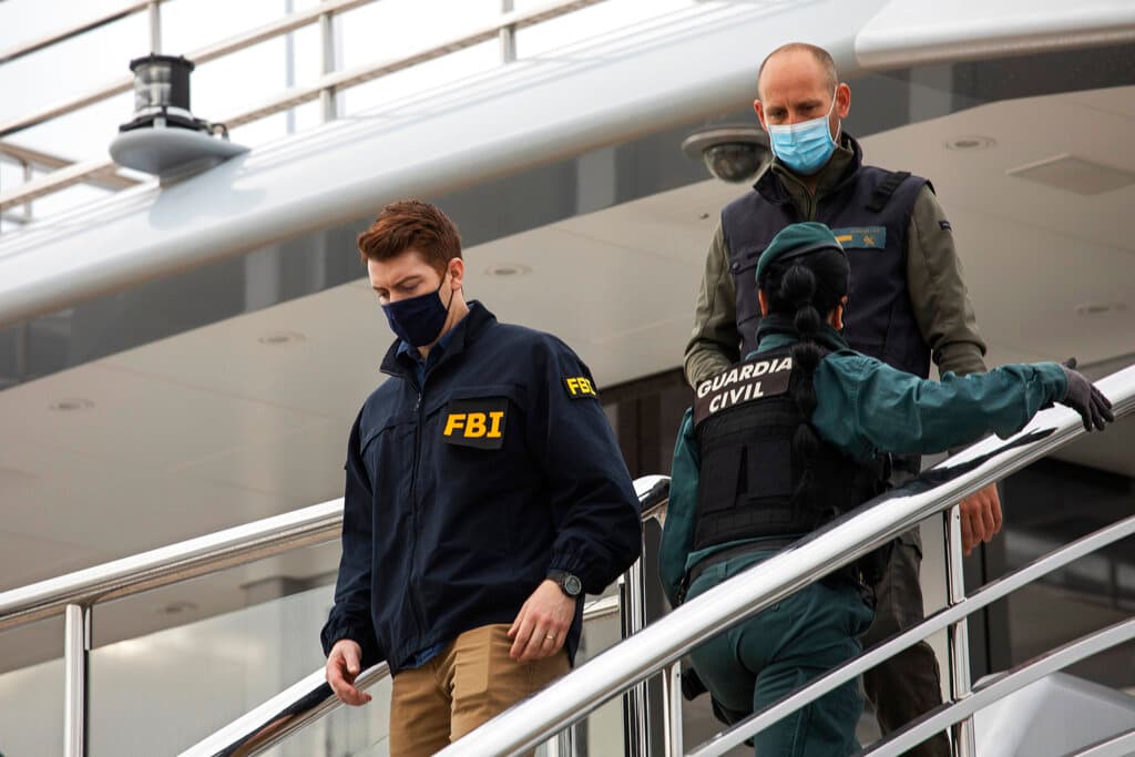 A federal agent walks past two Civil Guards on the yacht called Tango at Palma de Mallorca, Spain, April 4, 2022. AP/Francisco Ubilla