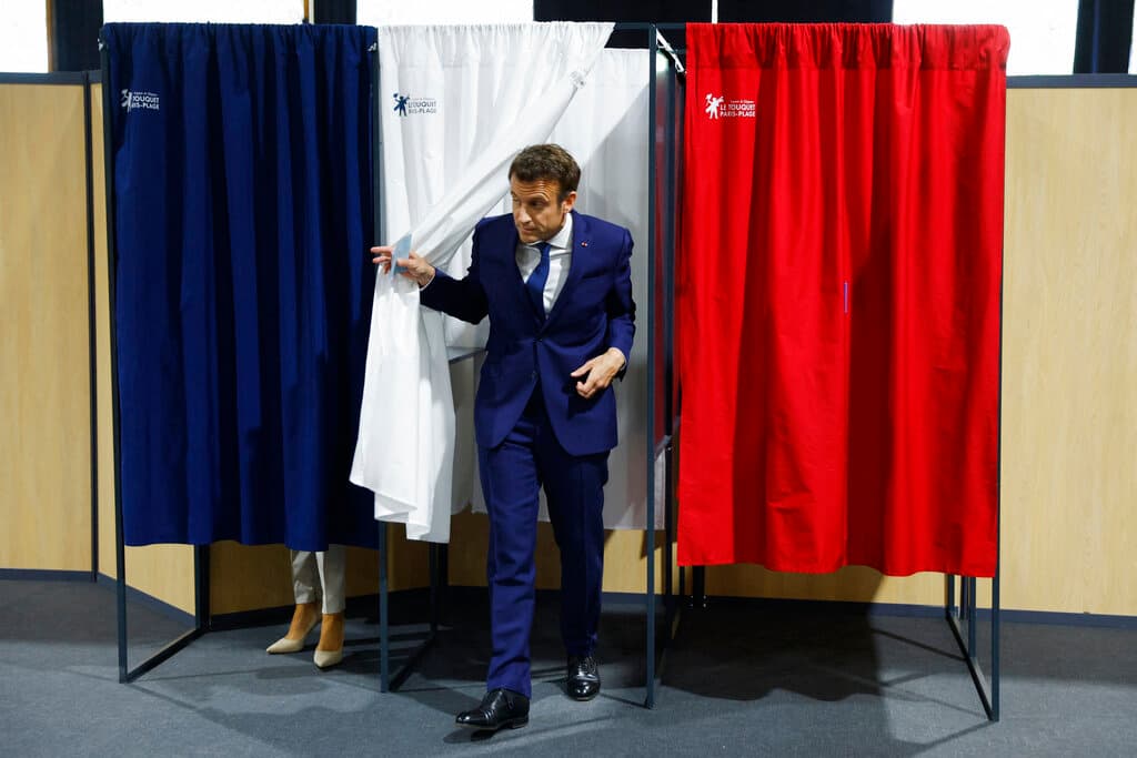 Presidentl Macron exits a voting booth April 24, 2022. Gonzalo Fuentes; pool via AP