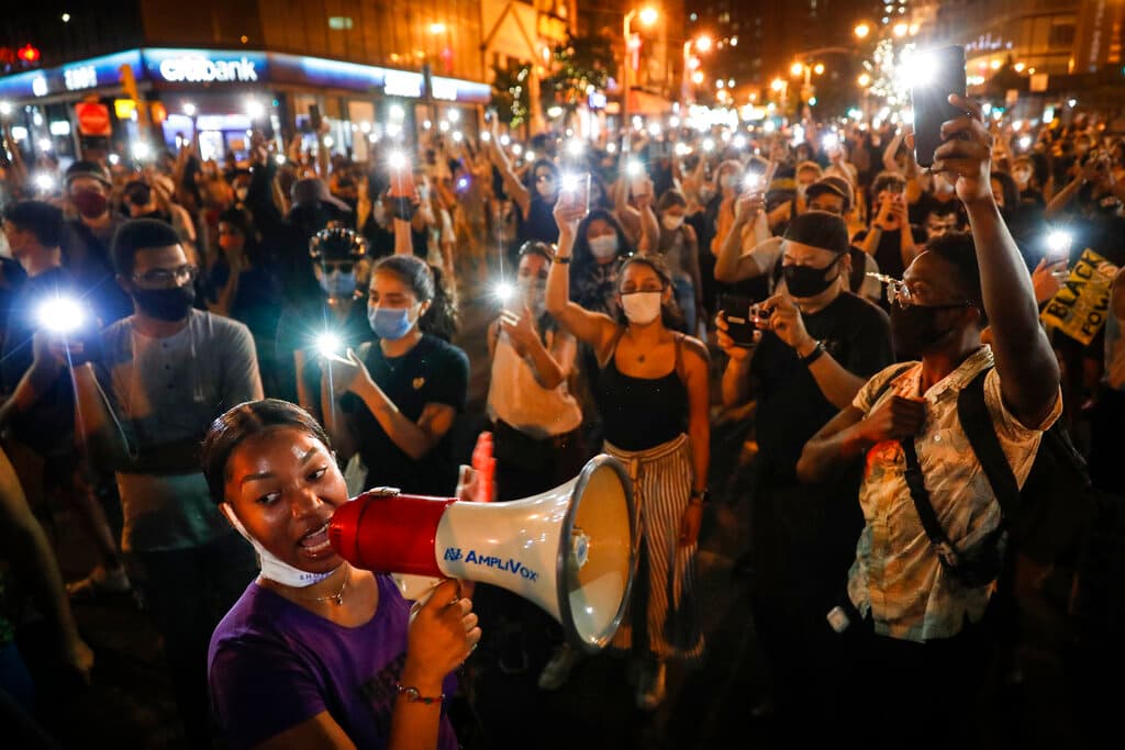 AP/John Minchillo Demonstrators raise their mobile phone lights during a protest in support of the Black Lives Matter movement at New York in July 2020.