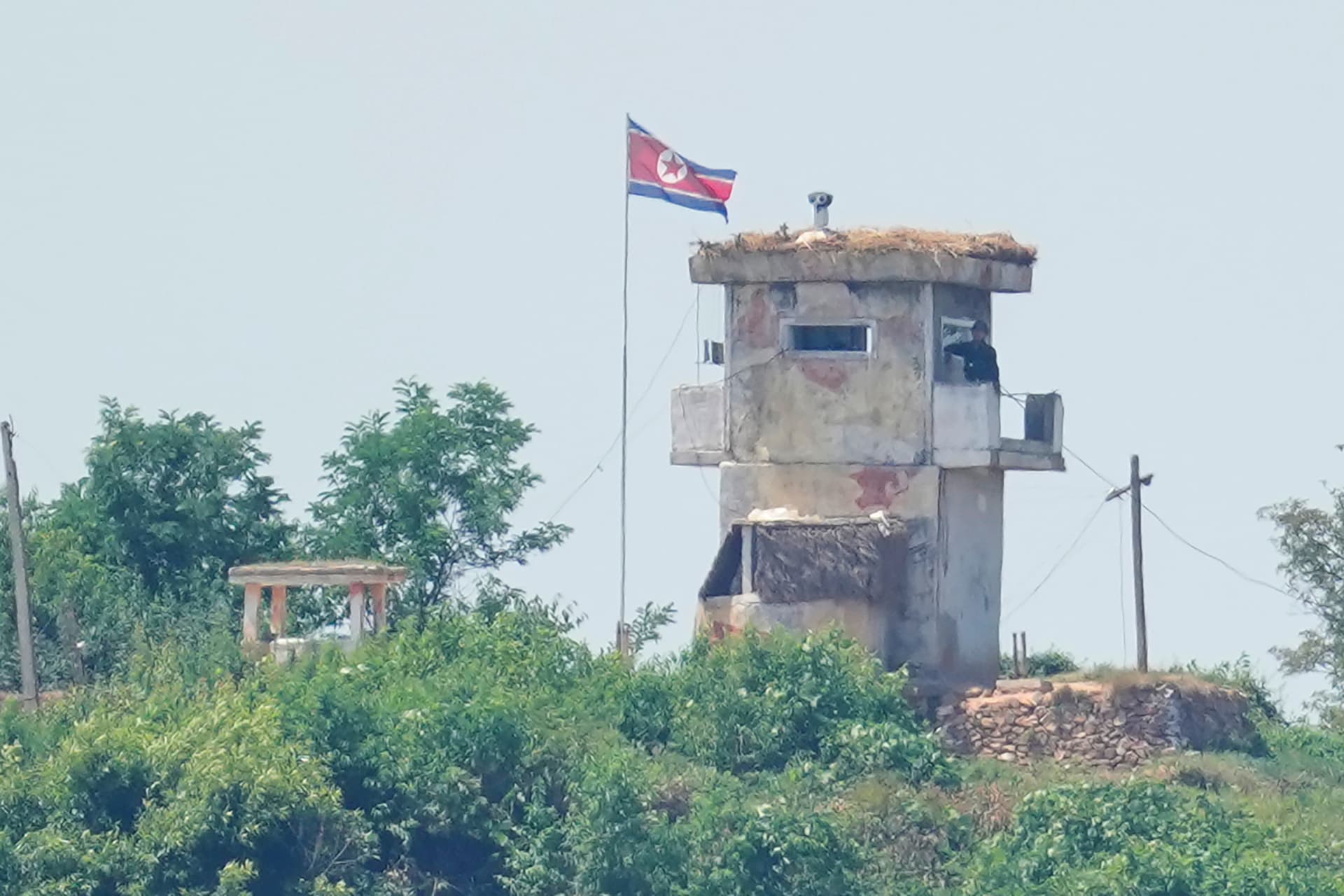 AP/Lee Jin-man A soldier stands at a North Korean military guard post flying a national flag, seen from Paju, South Korea.