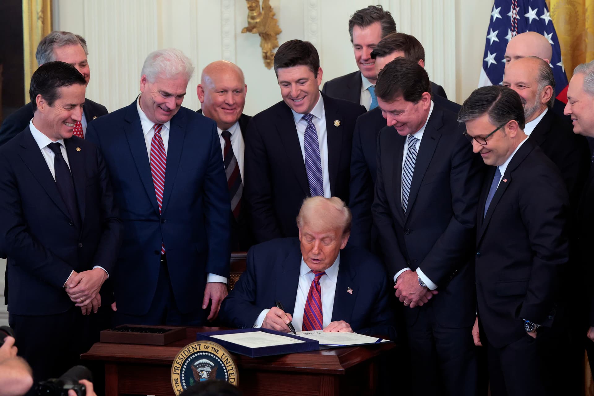 Anna Moneymaker/Getty Images President Trump, surrounded by lawmakers, signs the 'GENIUS Act' into law during a ceremony in the East Room of the White House on July 18, 2025.