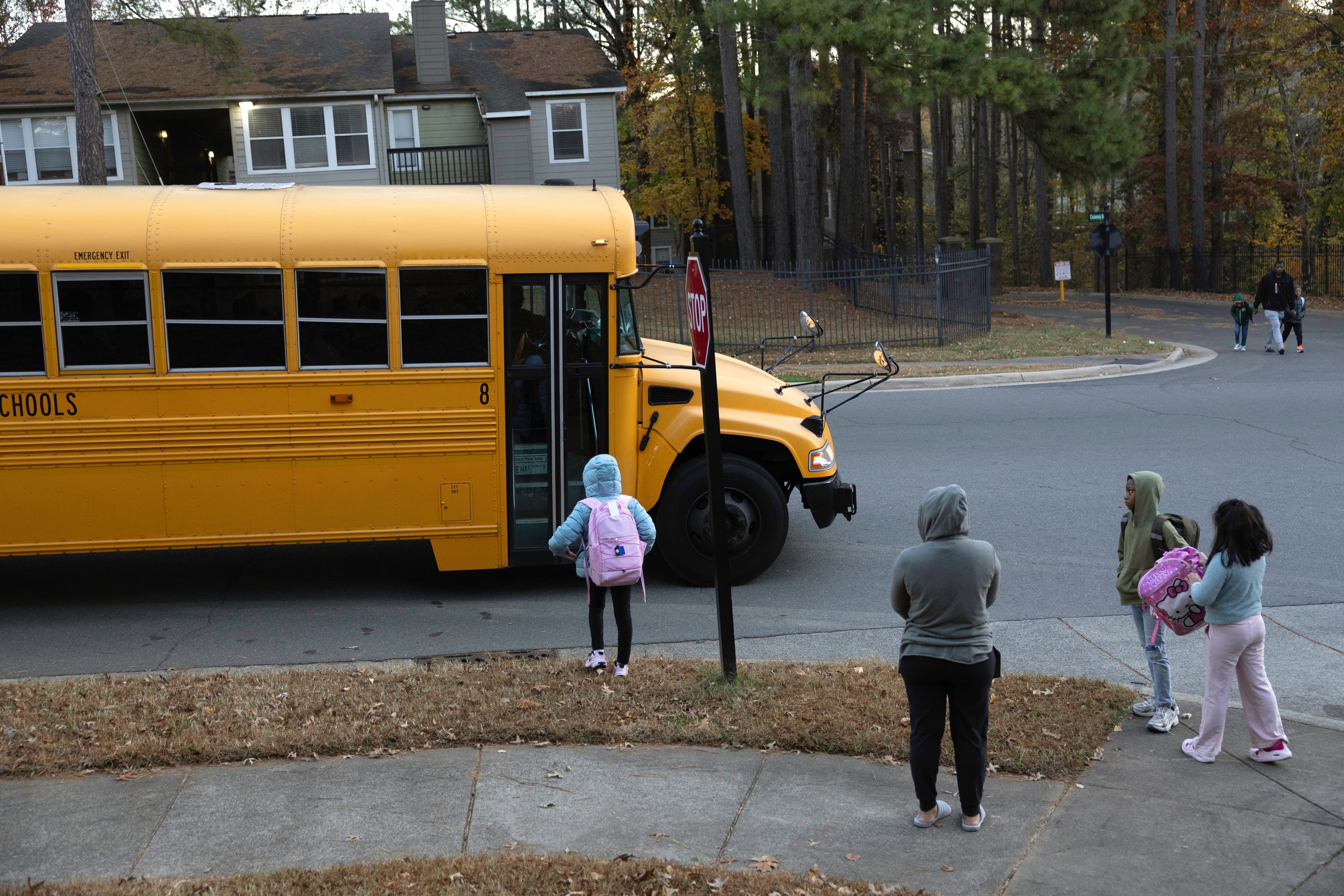 Students wait to board a school bus. Students wait to board a school bus.