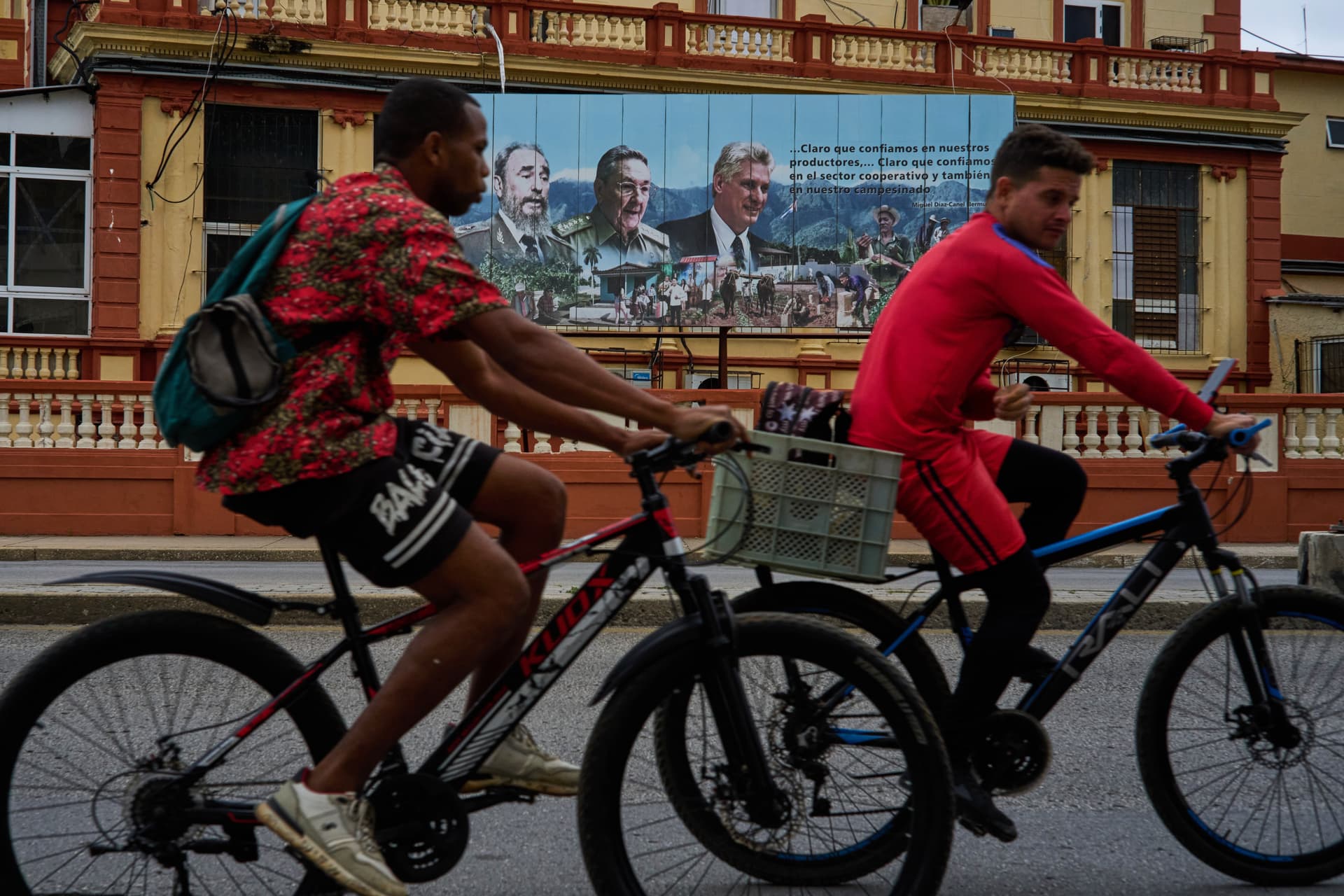 Ramon Espinosa/AP Cyclists pass in front of images of Cuba’s past presidents, Fidel Castro and Raul Castro, and its current president, Miguel Diaz-Canel, at Havana on March 18, 2026.