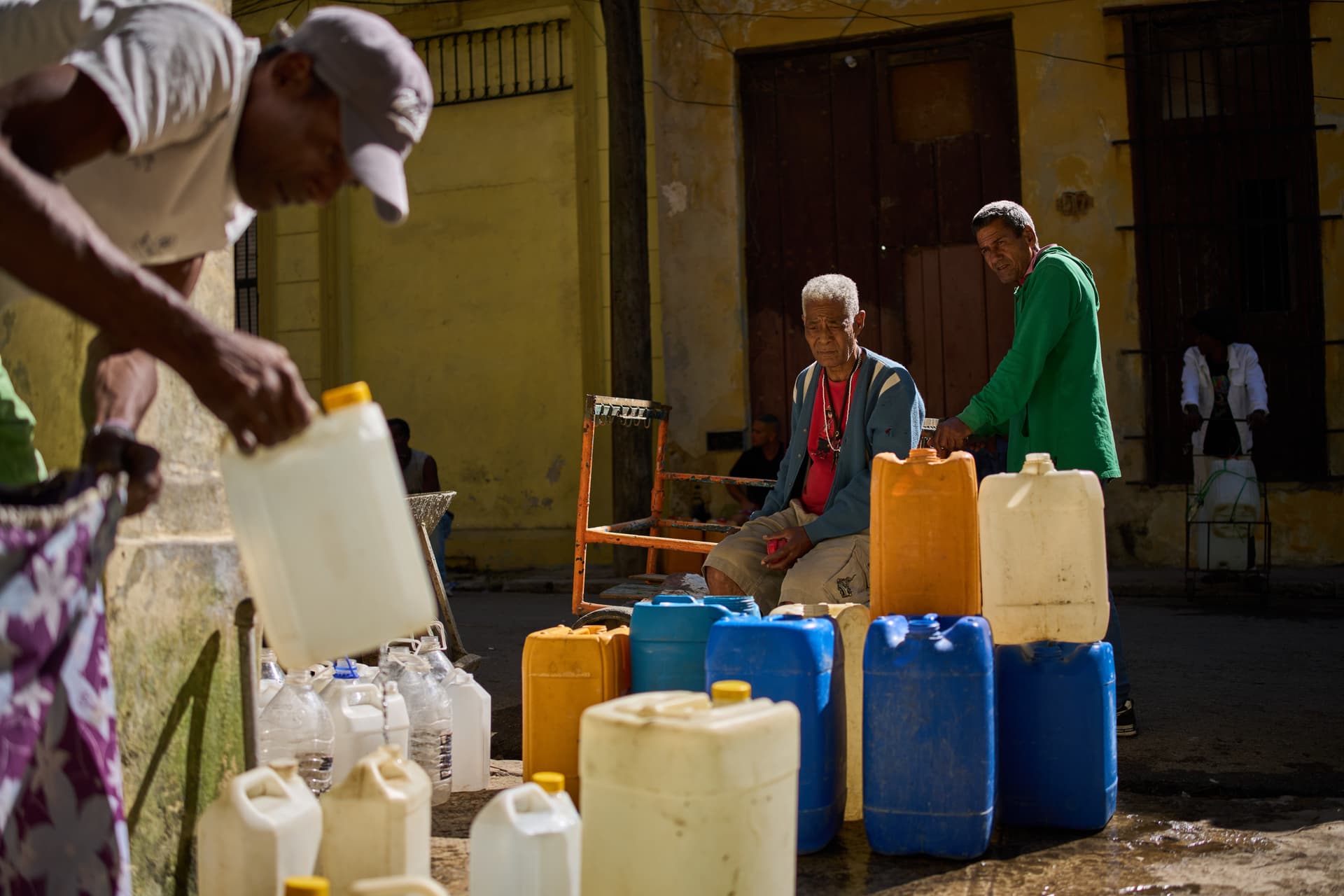 Ramon Espinosa/AP A man fills containers with potable water during a blackout at Havana on March 22, 2026.
