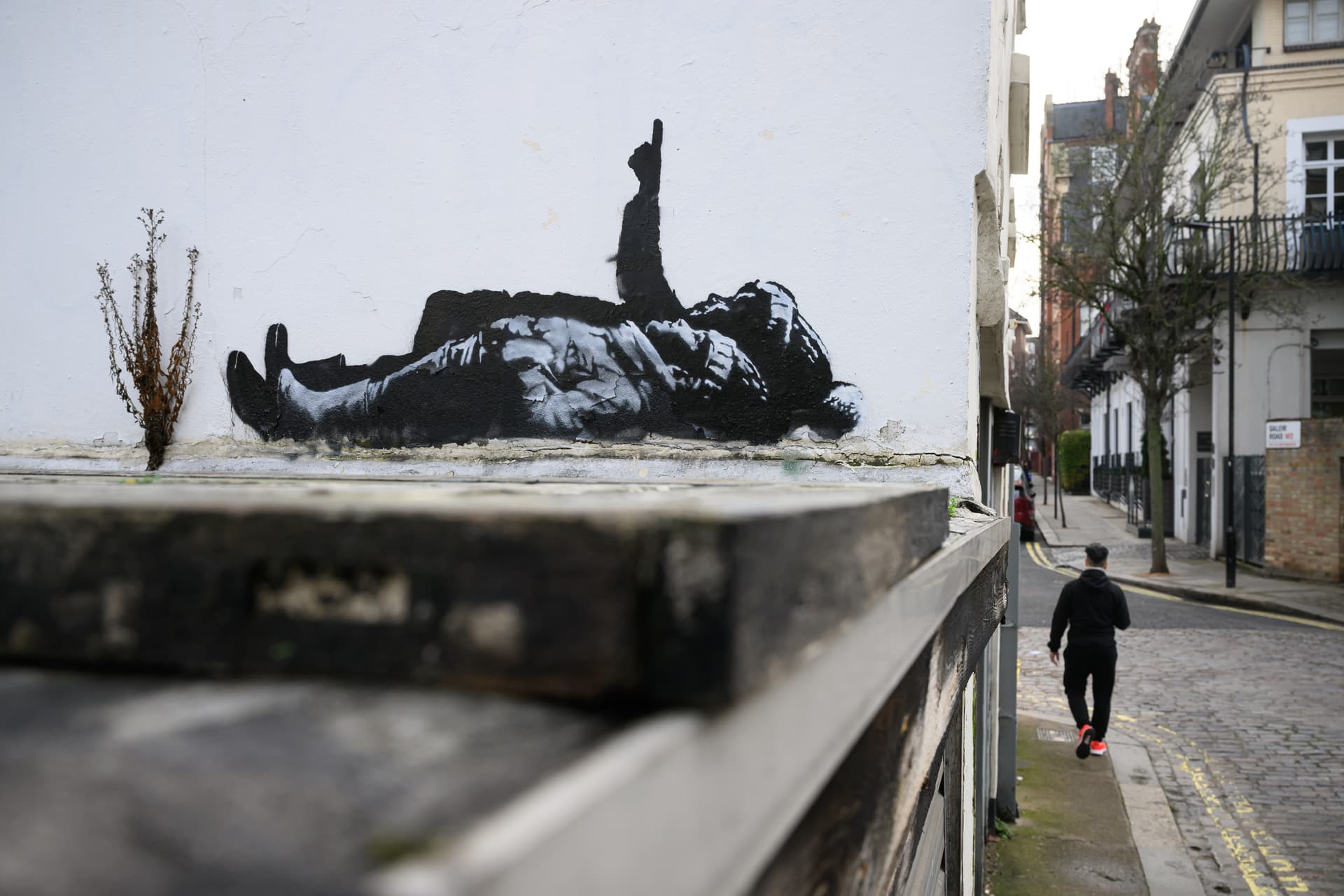 Leon Neal/Getty Images A man walks beneath a new Banksy artwork at London, England, on December 22, 2025.