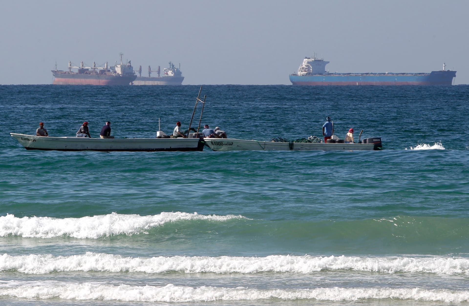 AP/Kamran Jebreili Fishermen work in front of oil tankers south of the Strait of Hormuz.