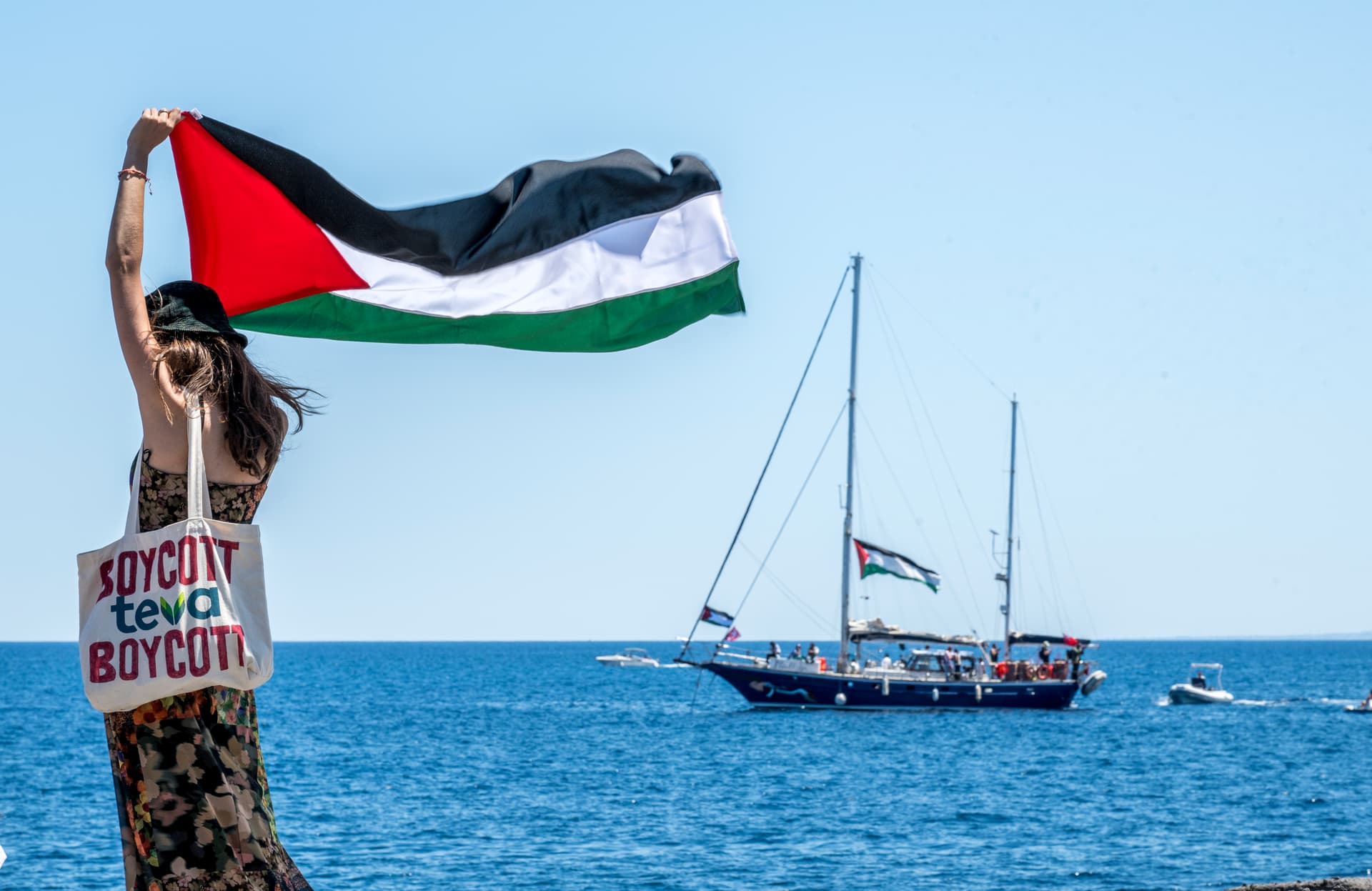 Fabrizio Villa/Getty Images A woman raises the Palestinian flag shortly before a ship sets sail for Gaza.