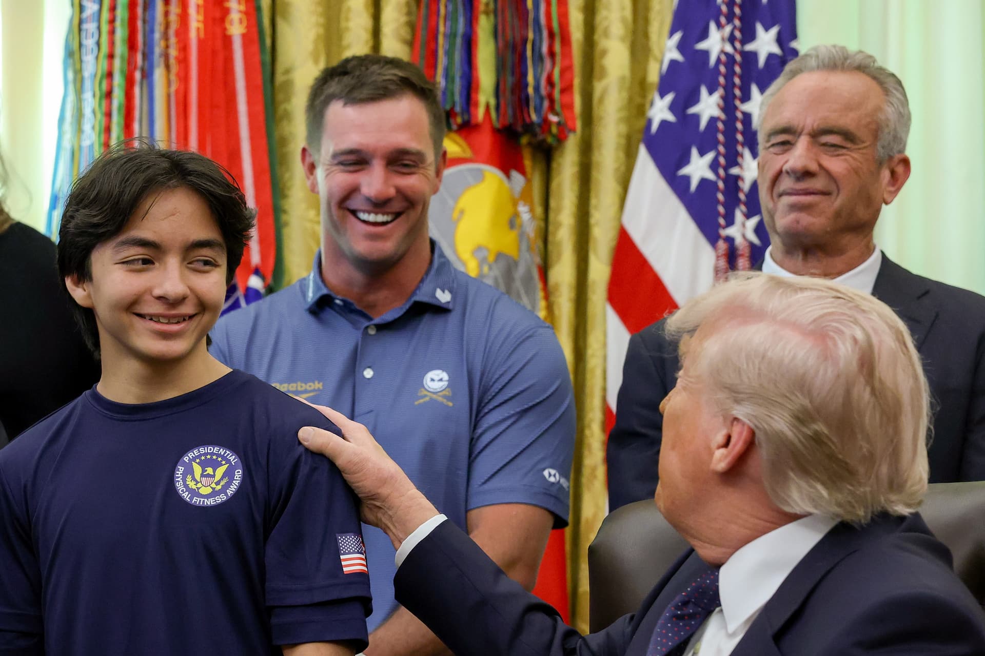 Anna Moneymaker/Getty Images President Trump speaks to young athletes as he is joined by (L-R) professional golfer Bryson DeChambeau and Secretary of Health and Human Services Robert F. Kennedy Jr. during a proclamation signing in the Oval Office of the White House on May 5, 2026 in Washington, D.C.