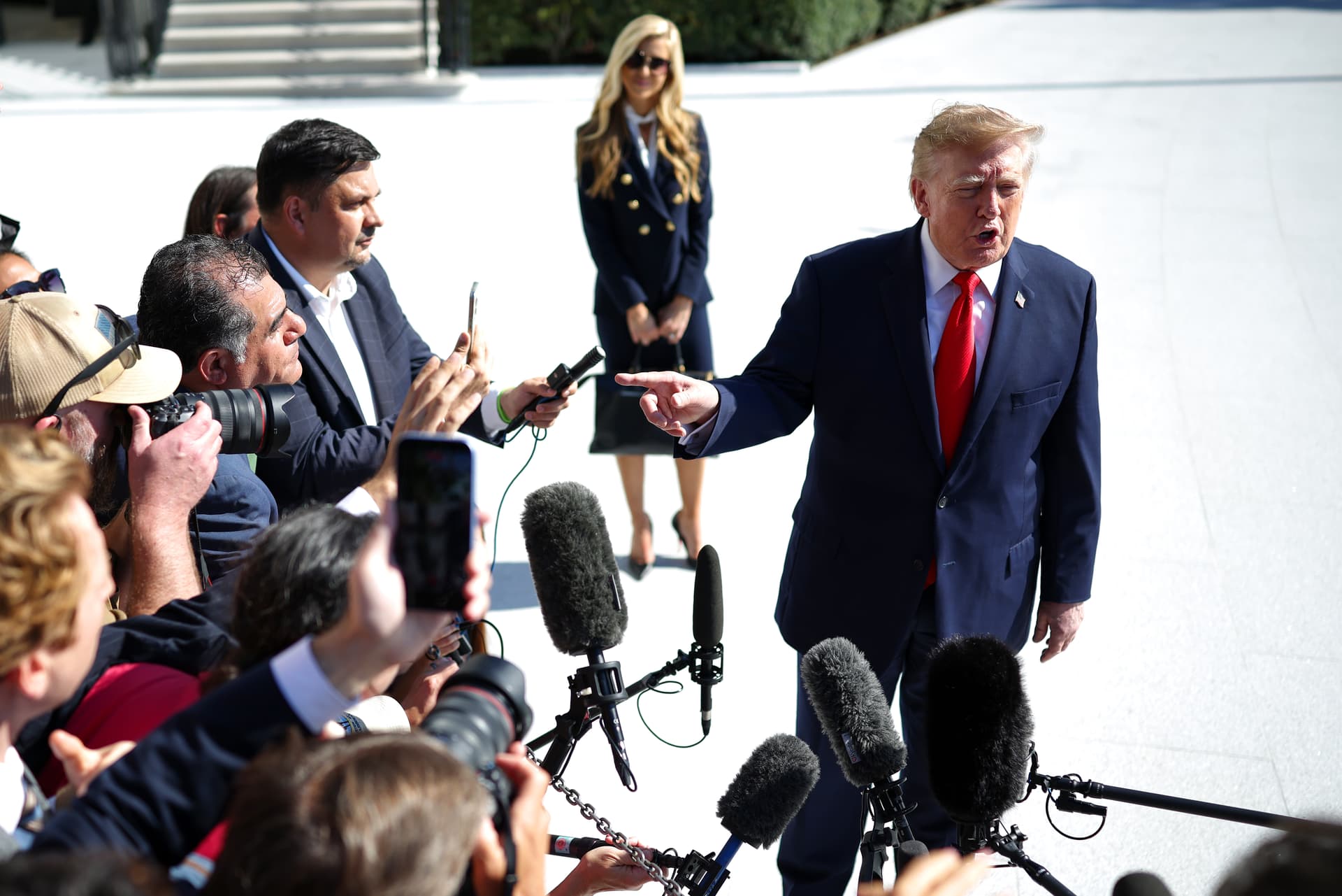 Win McNamee/Getty Images The White House press secretary, Katie Zacharia, looks on as President Trump speaks to reporters on the South Lawn of the White House before traveling to Alaska on October 13, 2026.