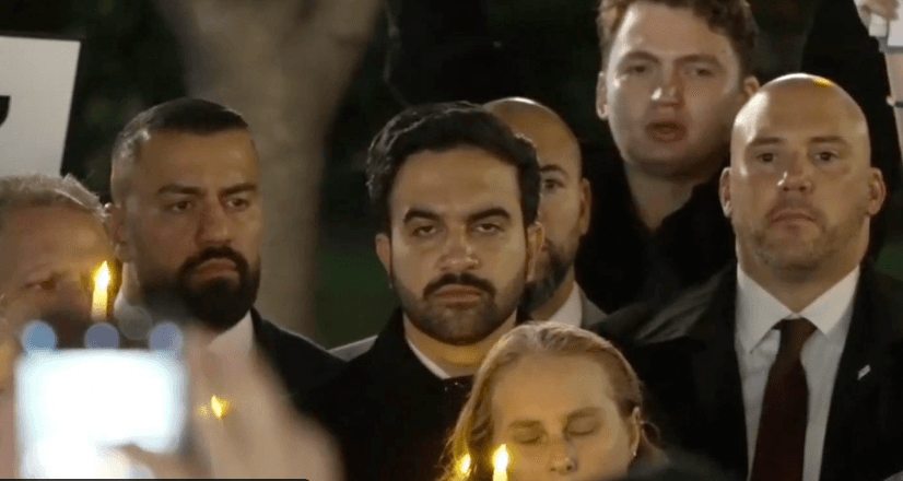 Via X Mayor Zohran Mamdani scowls as he is heckled at an October 7 vigil at New York City.